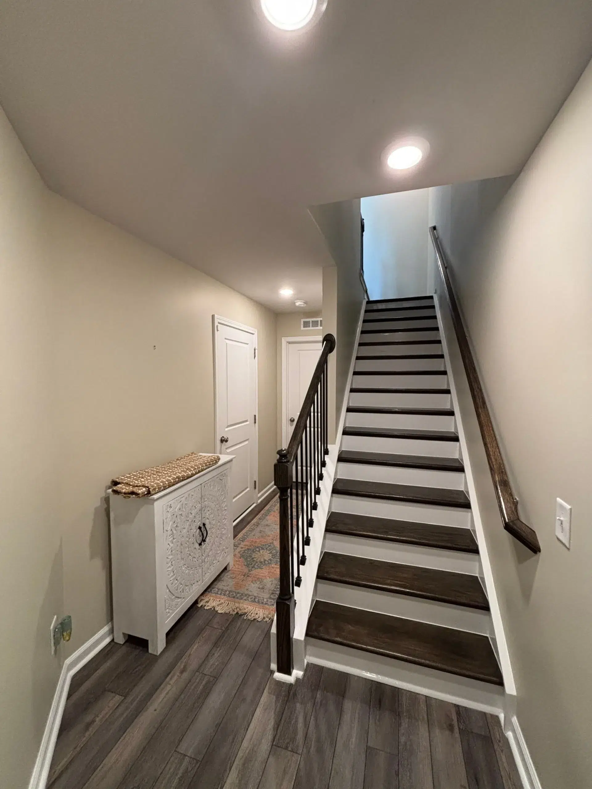 Modern Interior Staircase with Freshly Painted Walls and Treads Elegant interior staircase featuring dark wood treads, white risers, and freshly painted light beige walls.