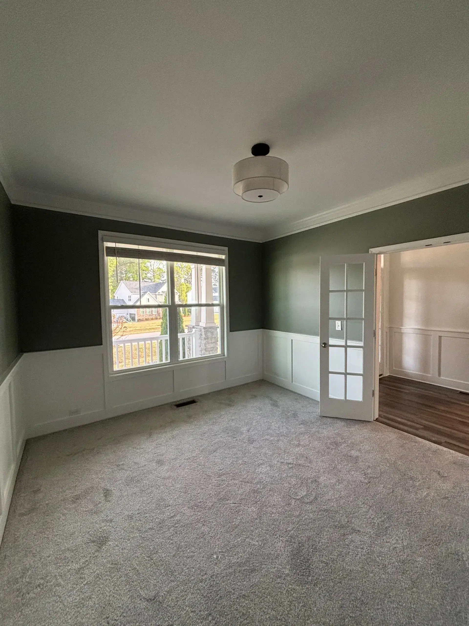 Stylish Two Tone Interior Painting with Wainscoting and Green Walls A room showcasing professional two tone interior painting with dark green walls and white wainscoting.