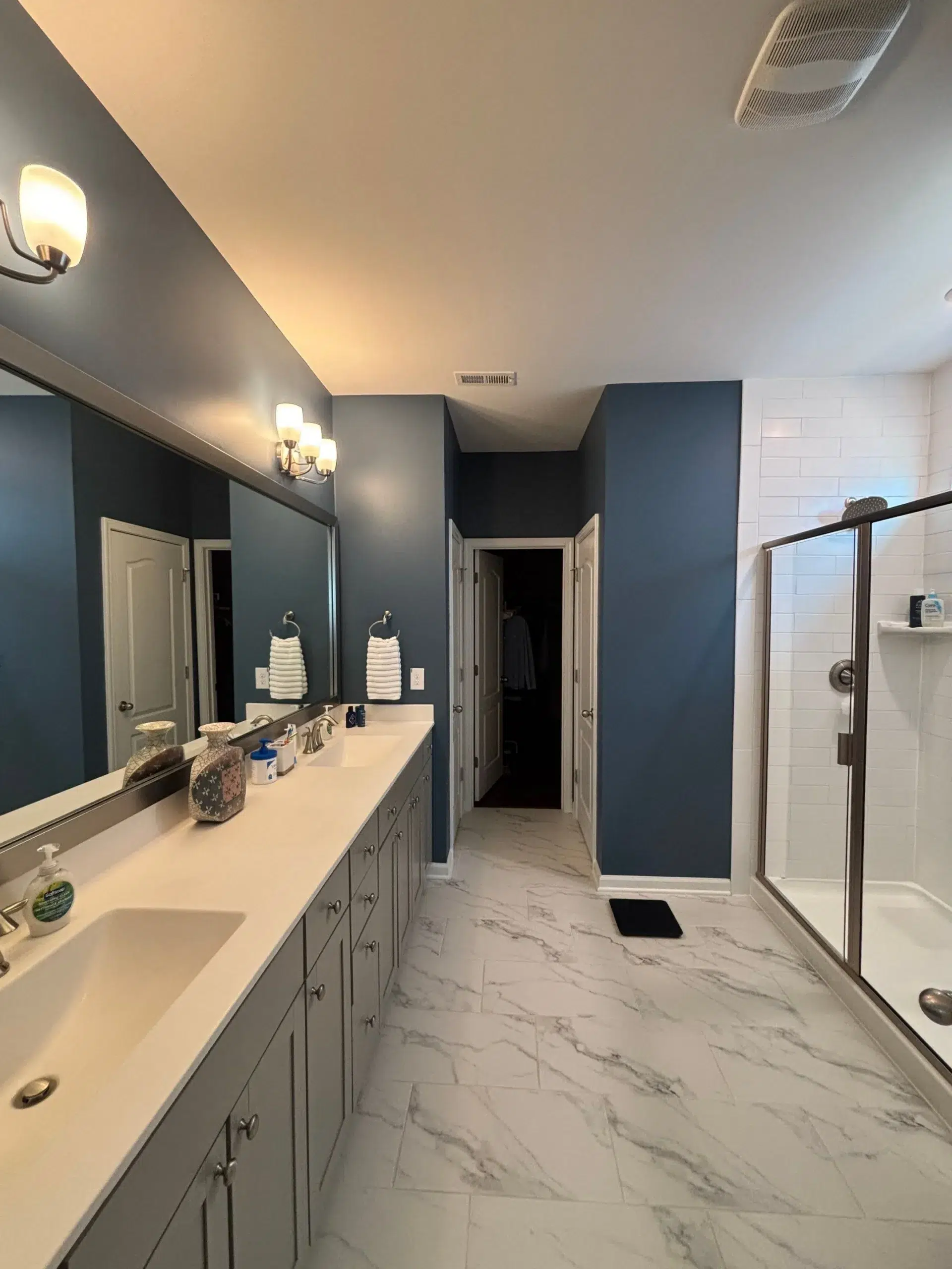 Modern Bathroom Interior Painting with Accent Wall and Vanity A contemporary bathroom showcasing a dark blue accent wall and freshly painted grey vanity cabinets.