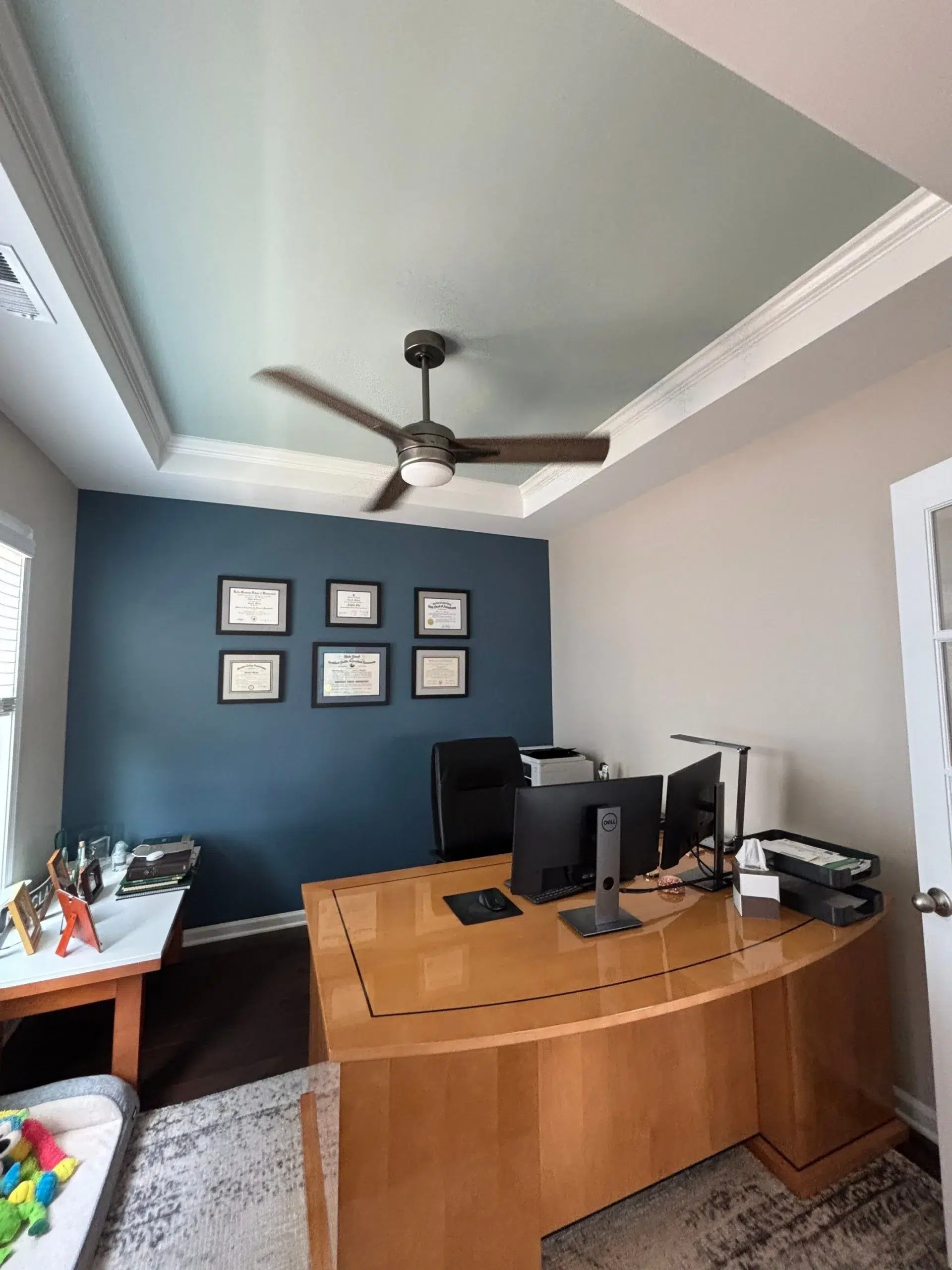 Professional Home Office Interior Painting with Accent Wall and Ceiling A stylish home office featuring a dark blue accent wall and a light blue painted tray ceiling.