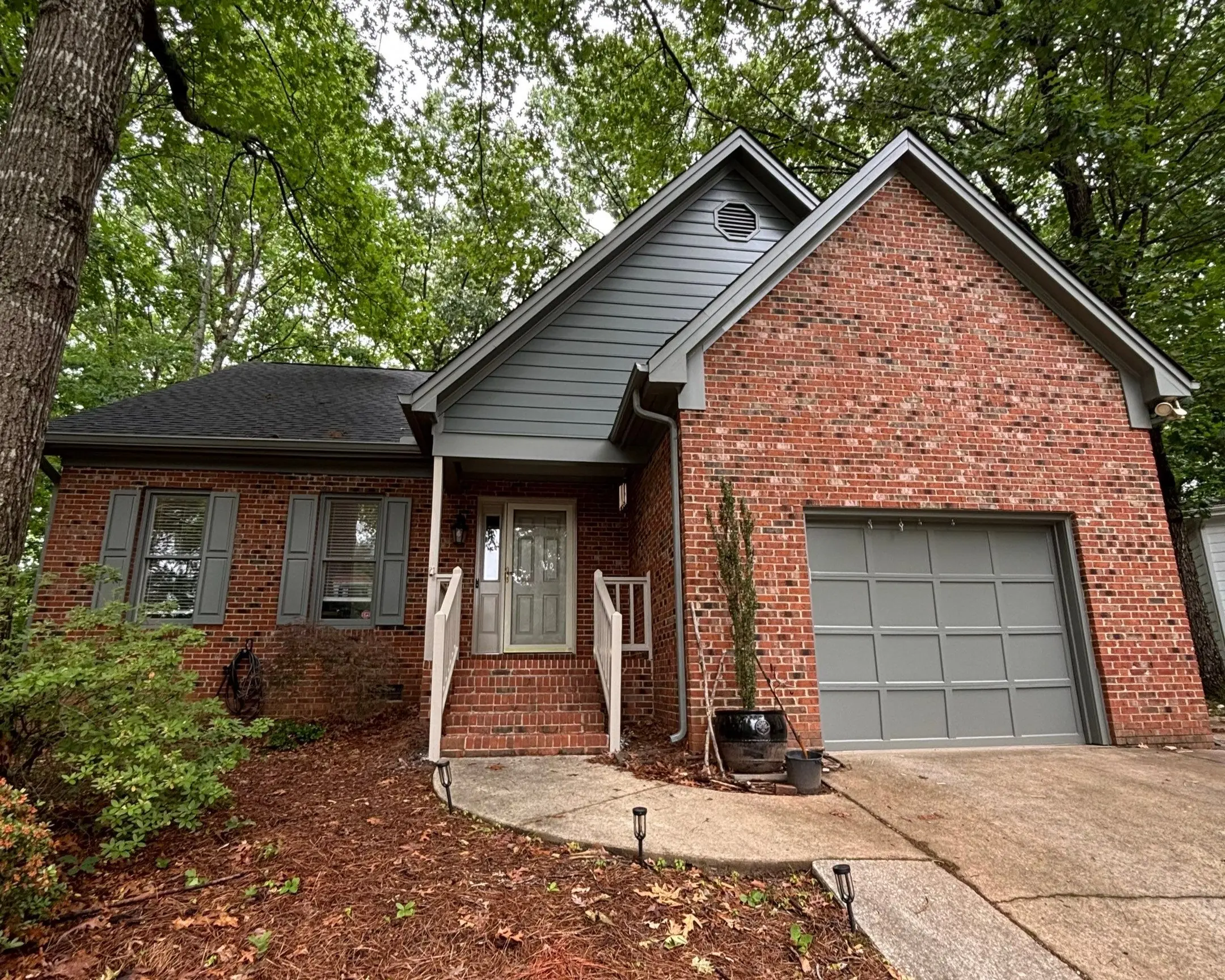Brick House with Gray Siding and Garage Door Painting A brick house with newly painted gray siding, shutters, and garage door.