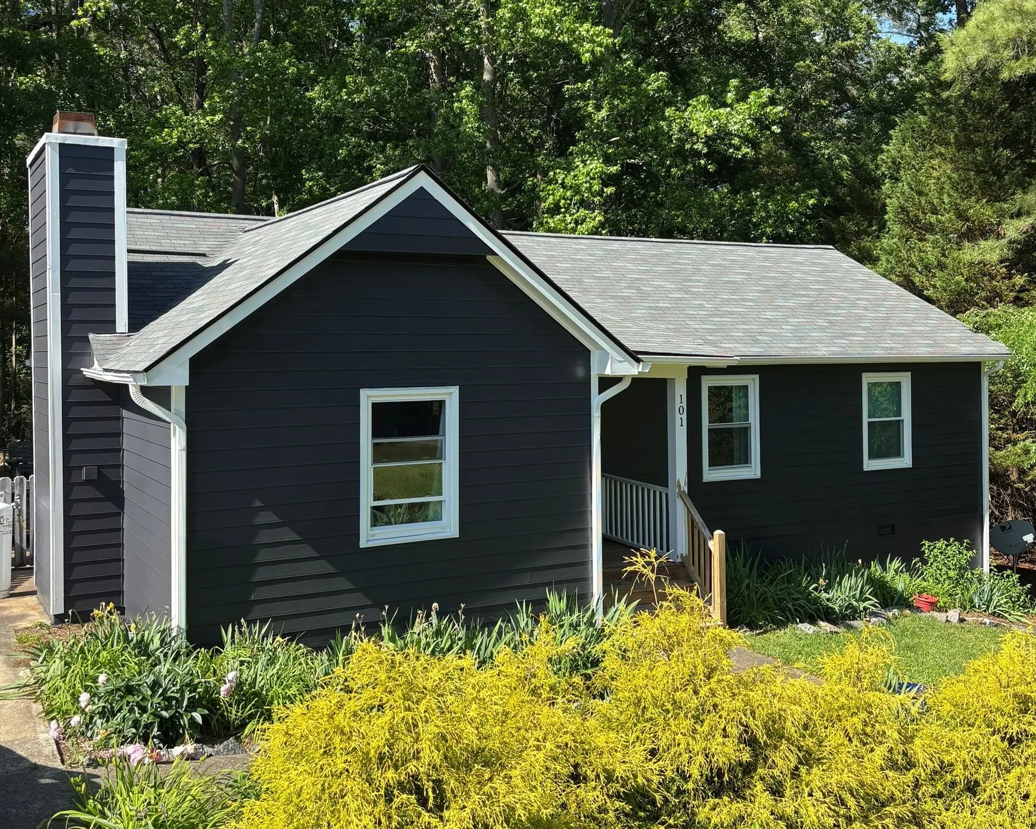 Residential Exterior Painting Dark Siding White Accents A newly painted dark blue house with white window frames and porch railing.