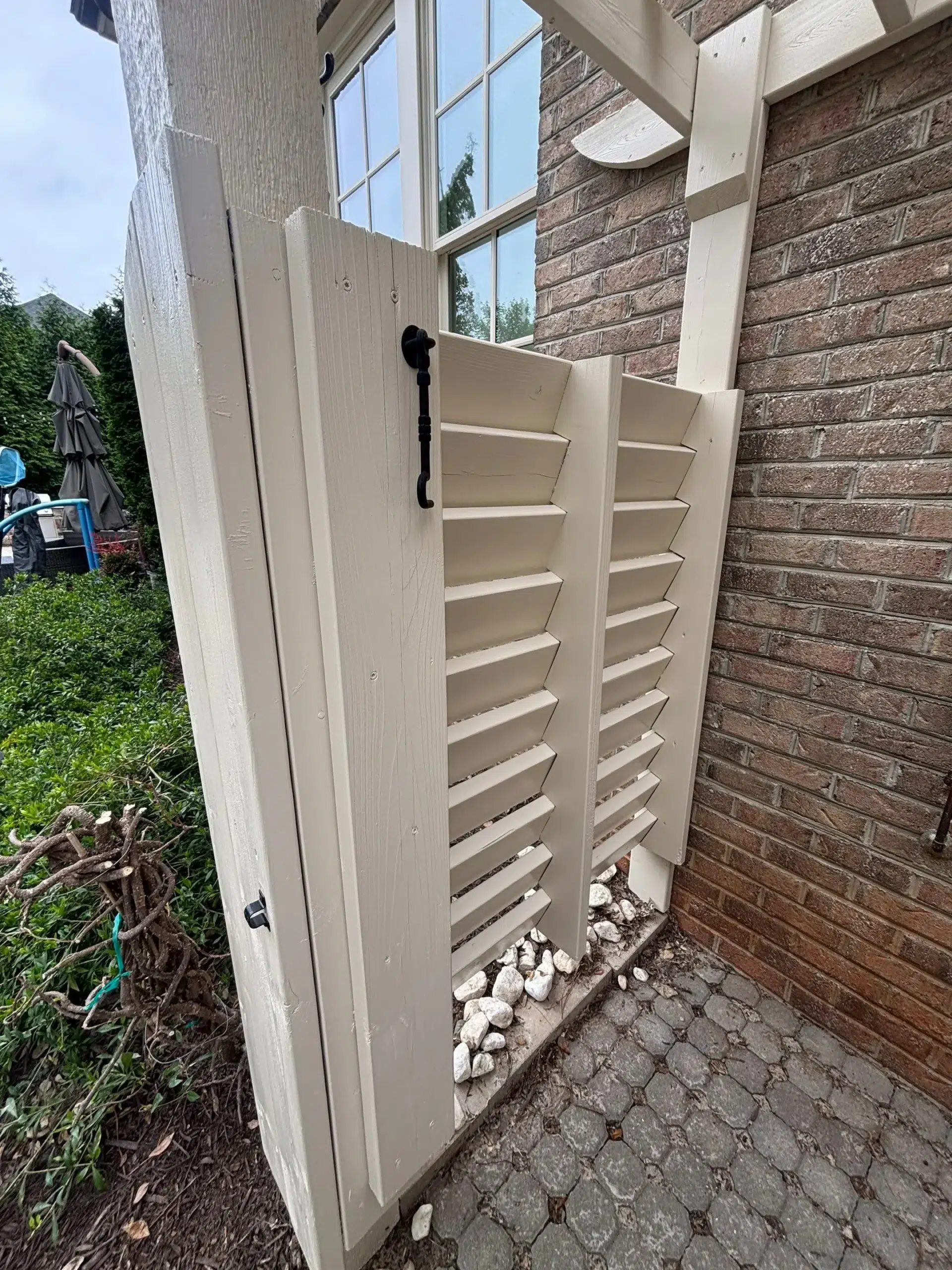 Outdoor Shower Privacy Screen Painting Light Beige A freshly painted light beige outdoor shower privacy screen next to a brick wall.