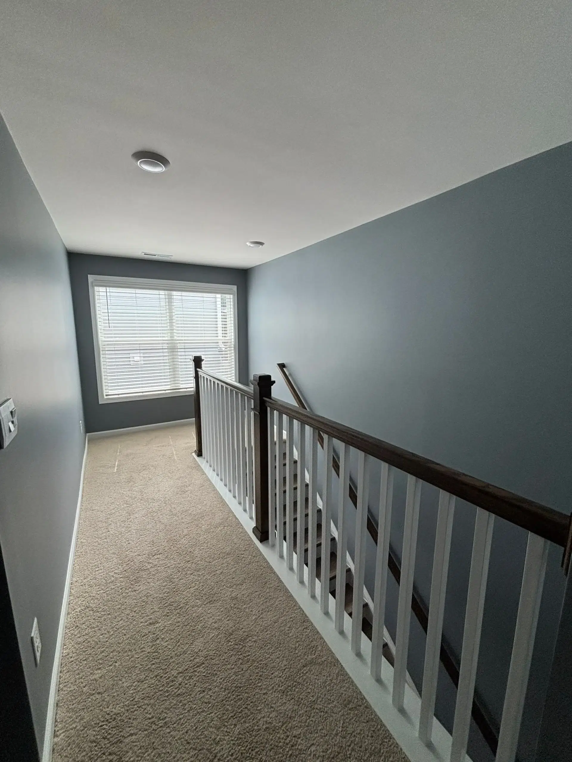 Modern Hallway Interior Painting with Accent Walls A freshly painted interior hallway featuring dark blue gray walls, white trim, and a stylish staircase banister.