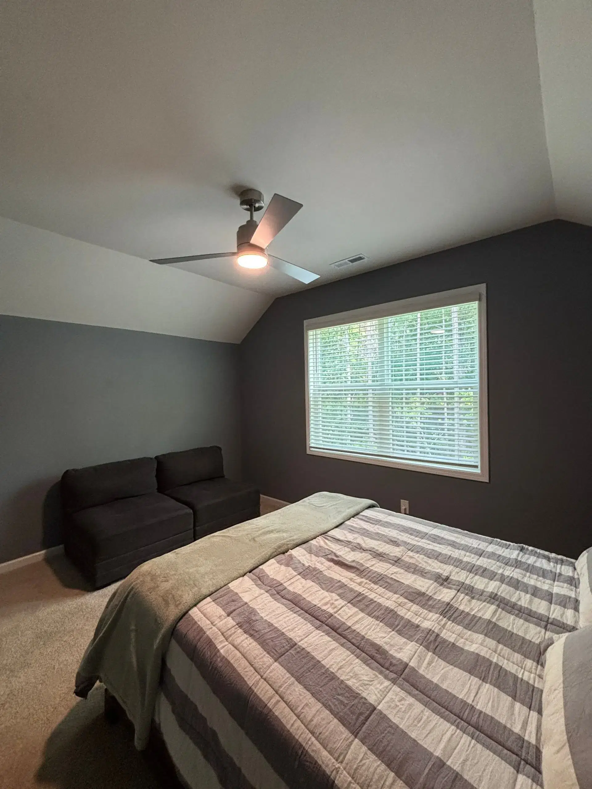Contemporary Bedroom Interior Painting Services A cozy bedroom with dark blue gray walls, a white ceiling, and a large window, showcasing fresh interior paint.