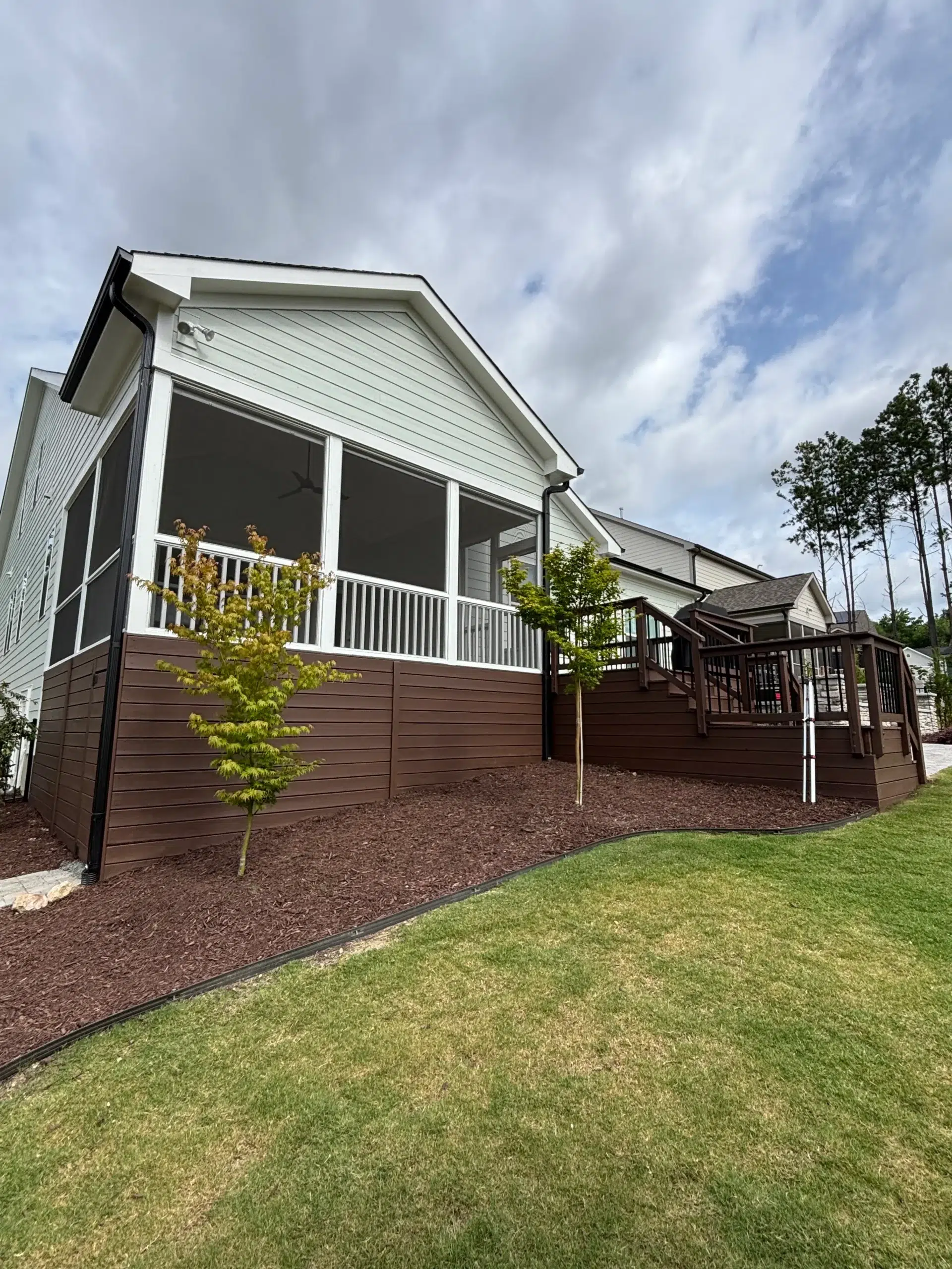 Professional Exterior House Painting and Deck Staining Services Beautiful home exterior featuring freshly painted light green siding and a dark brown stained deck.