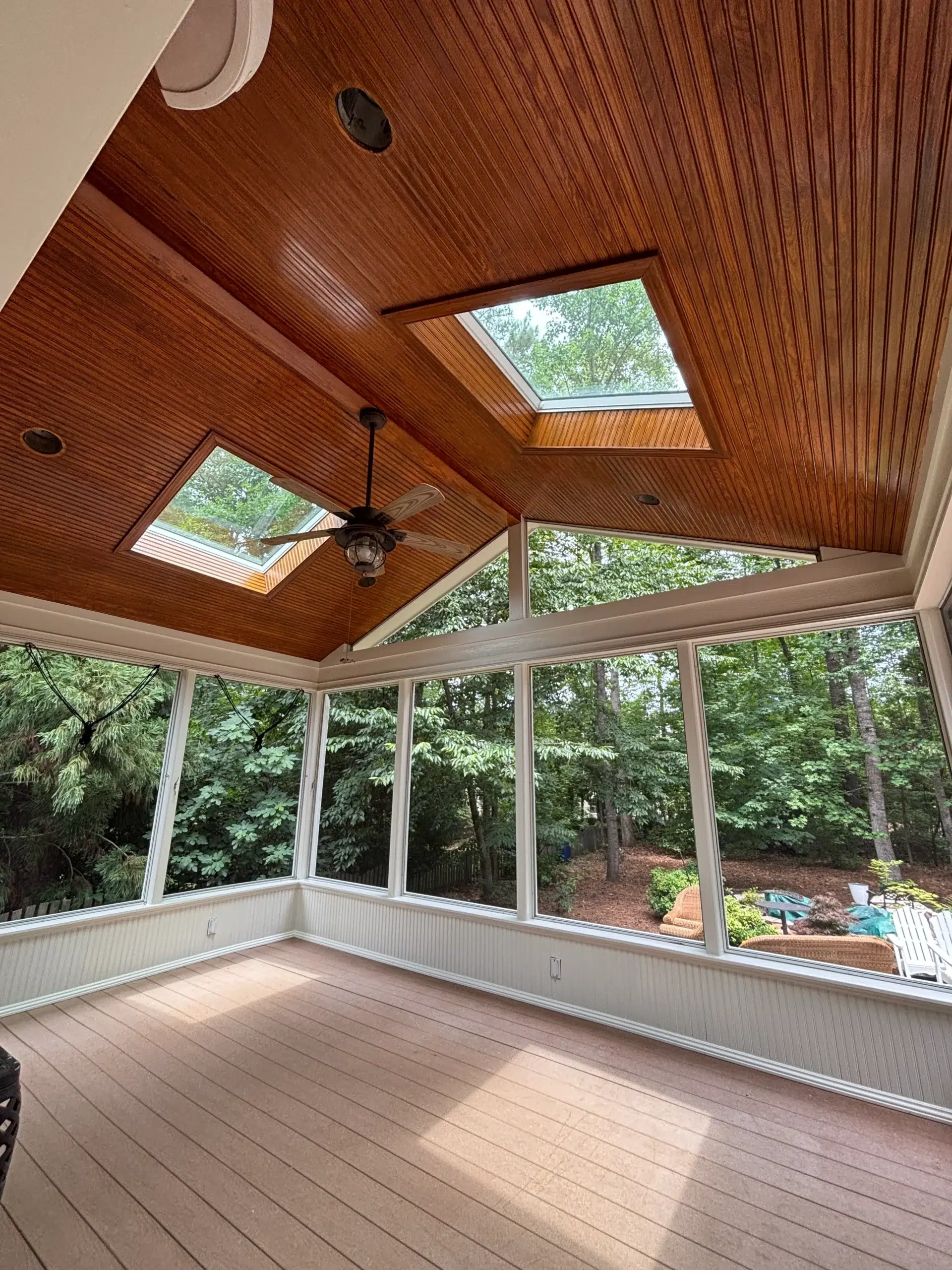 Screened Porch Interior Painting and Wood Ceiling Staining Bright screened porch interior with stained wood plank ceiling, skylights, and white wainscoting.