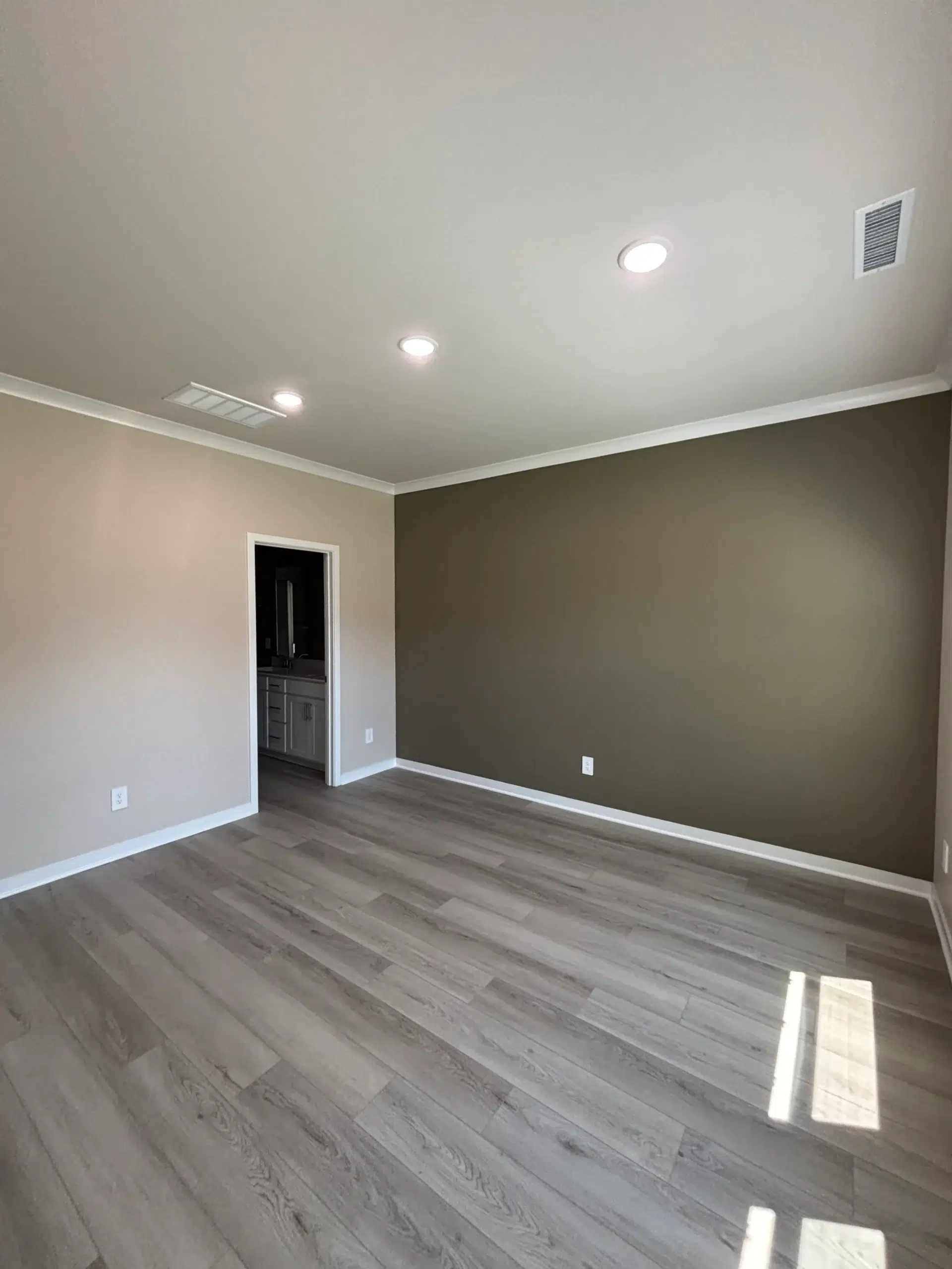 Stylish Two Tone Interior Room Painting with Accent Wall An empty room featuring a stylish two tone paint job with a dark accent wall and light beige walls.