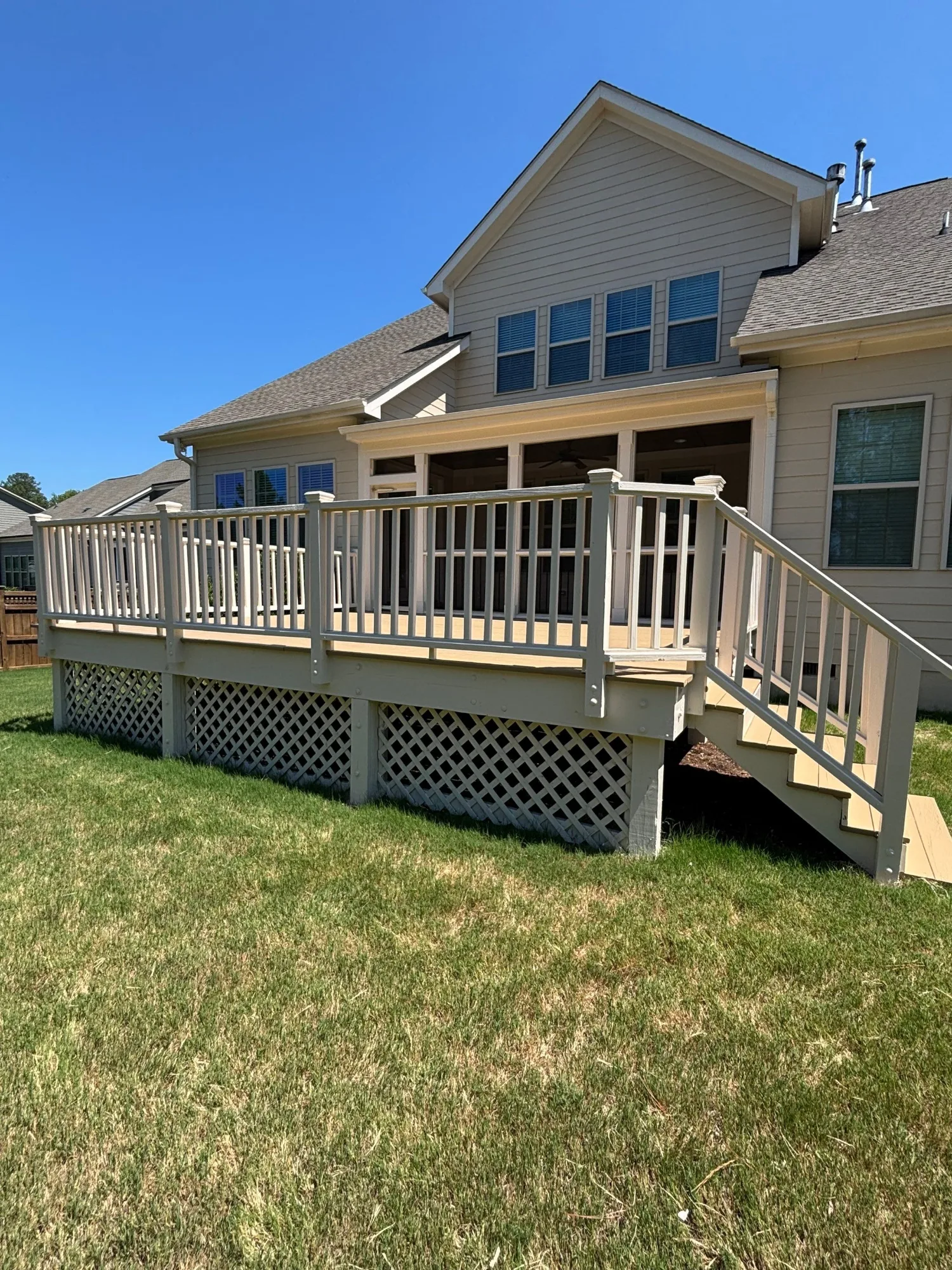 Tan Composite Deck with White Railings Tan-painted composite deck with white vertical railings and steps attached to gray fiber cement siding home in Cary NC