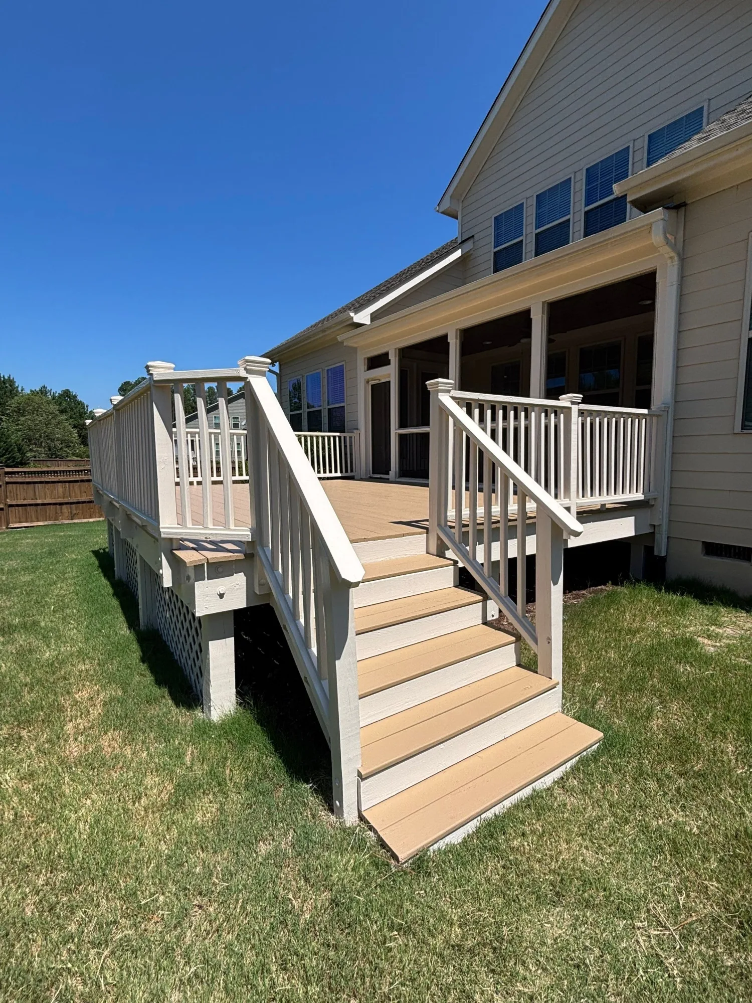 Tan Composite Deck with White Railings Tan-stained composite deck with white vertical railings and steps attached to gray fiber cement siding home