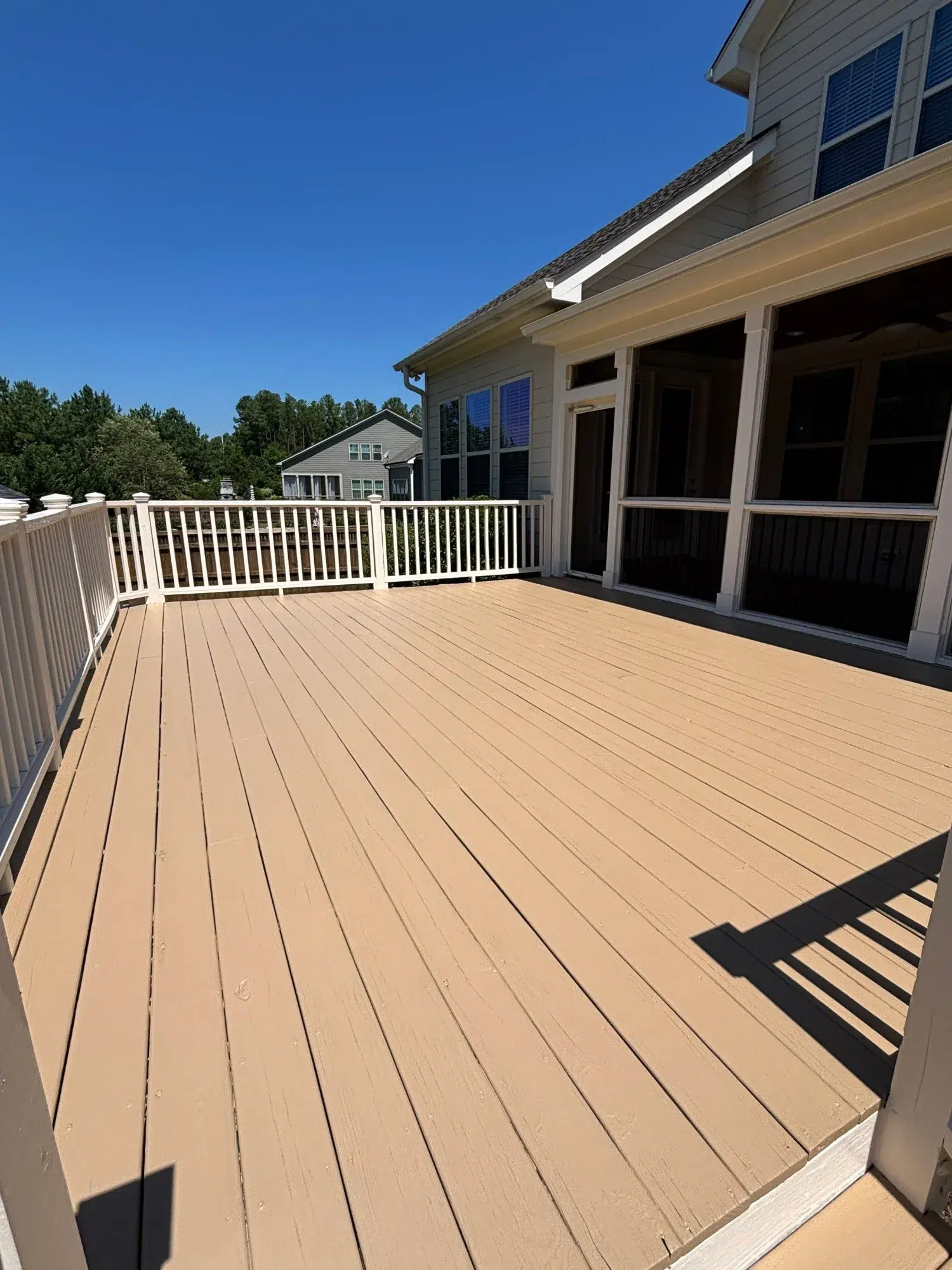 Tan Painted Deck with White Railings Tan-painted composite deck with white vertical railings, screened porch, and blue-shuttered home exterior