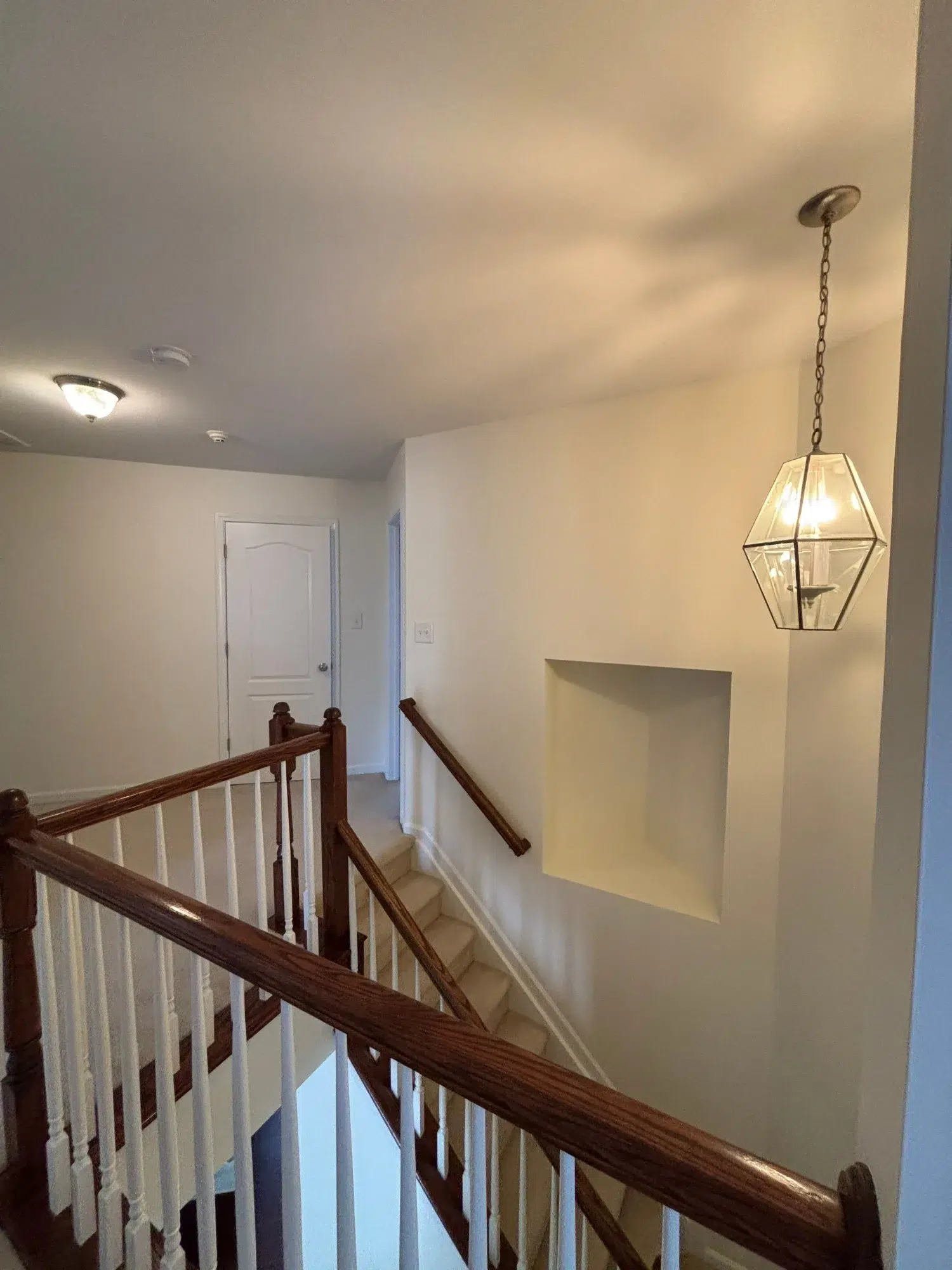 Cream Painted Stairwell Interior Cream-painted stairwell with white-trimmed walls, dark wood handrails, and geometric pendant light fixture