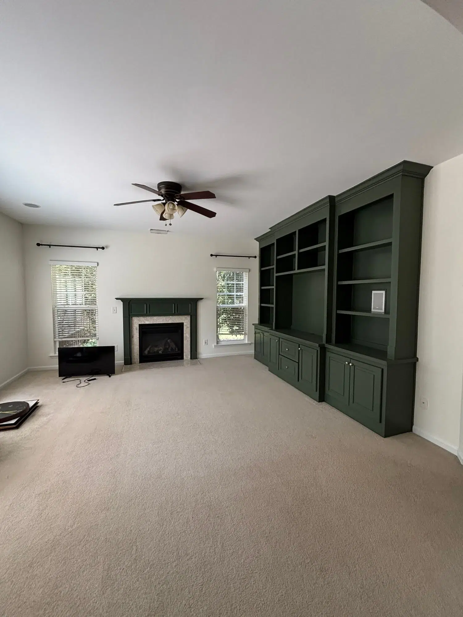 Green Cabinet Interior Living Room Cream-painted interior room with dark green painted built-in cabinetry, fireplace, and ceiling fan
